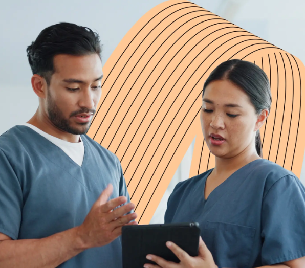 One man and one woman in nursing scrubs standing and discussing information on a tablet